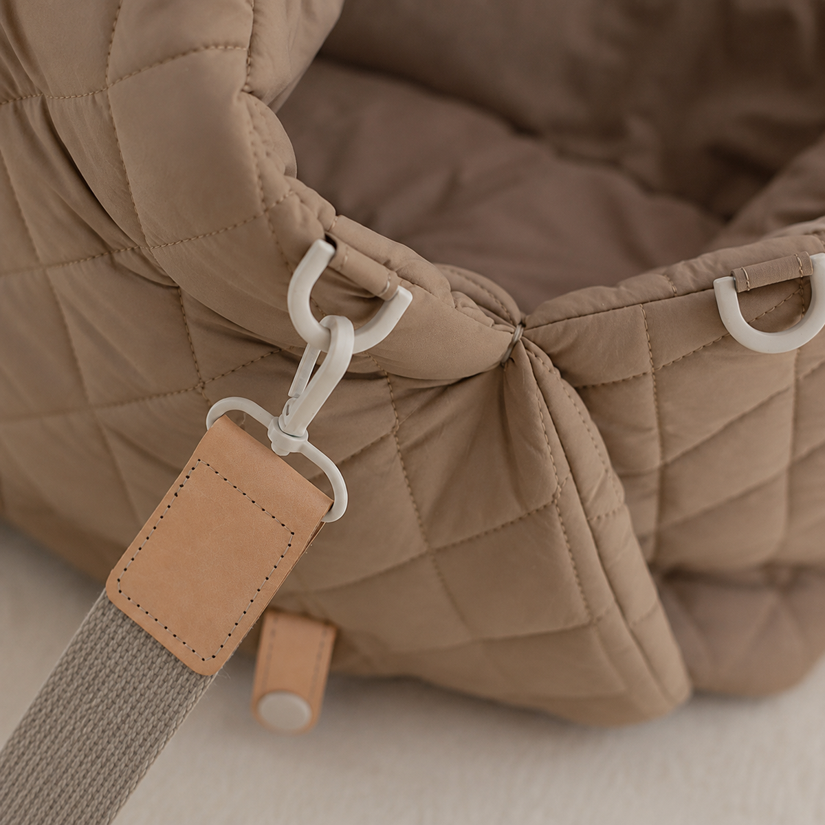 Khaki quilted pet carrier shoulder strap clip and hardware close-up