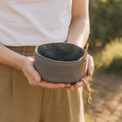 Person holding a gray TrailFold foldable travel dog bowl outdoors